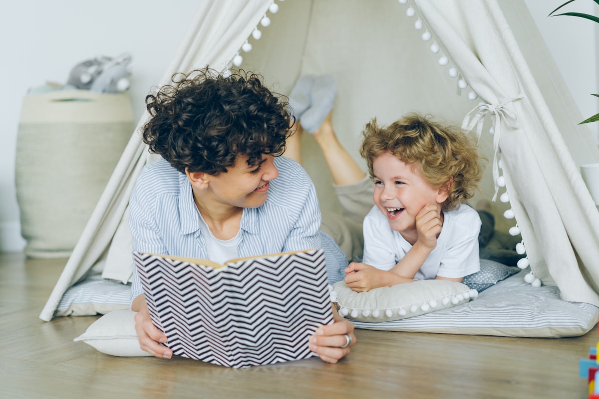 A parent sitting with a child, pointing at a book together